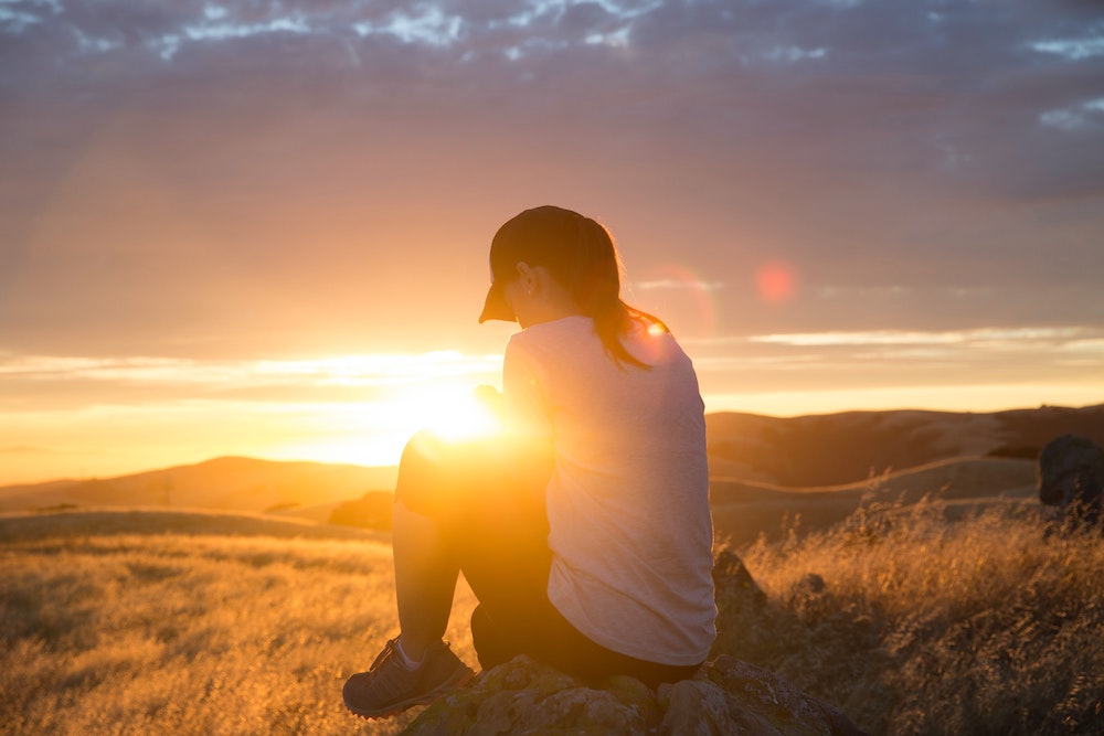Woman spending time in God's presence outside at sunset - waiting on God.  